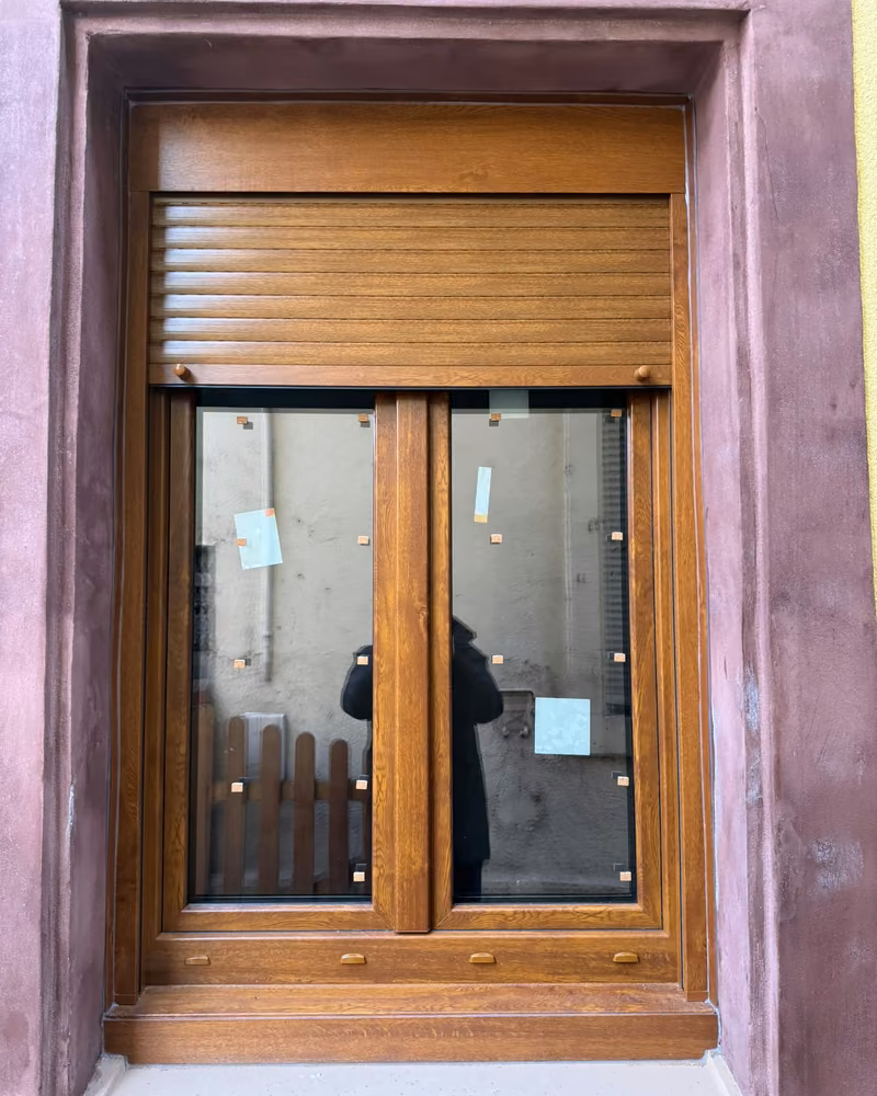 Fenêtre ton bois et volet roulant assorti dans son encadrement, juste après la pose, étiquettes encore sur le vitrage — photo de chantier